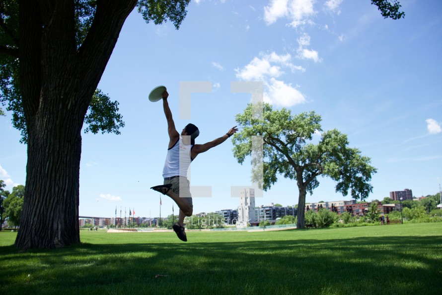 a young man catching a frisbee in a park 