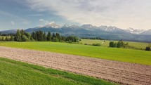Spring plowed field in rural agriculture nature, farming in green alpine landscape
