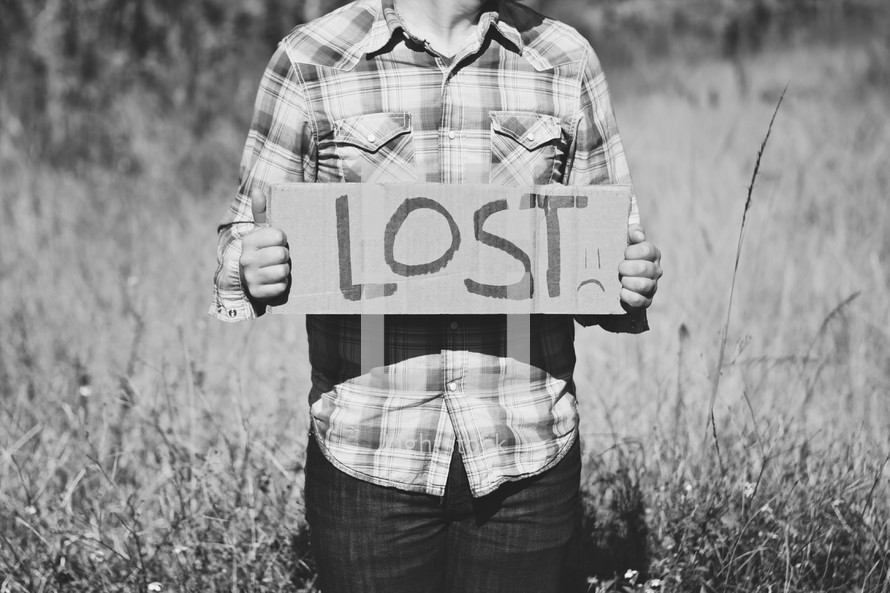 man holding a sign with the words LOST