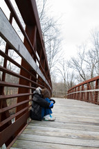 scared and sad woman crouched on a bridge 