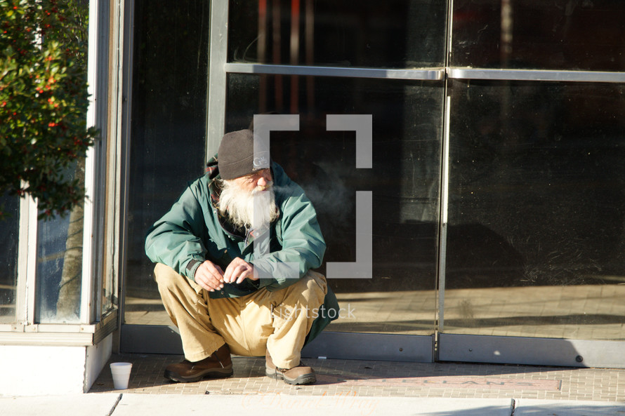 a homeless man sitting on a curb 