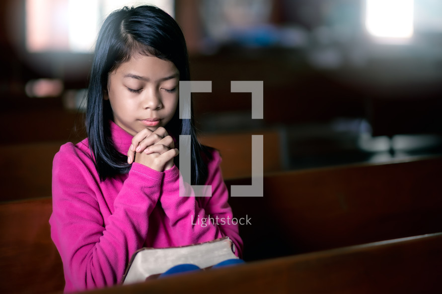 a girl praying in a church alone 