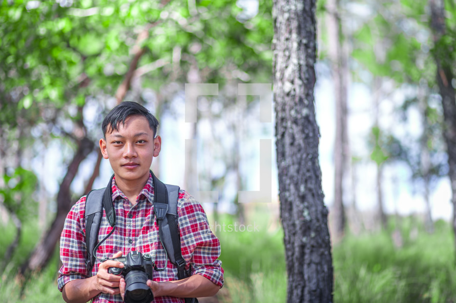 a man in a forest holding a camera 