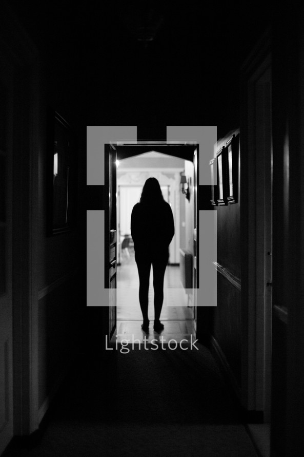 silhouette of a woman standing in a dark hallway 