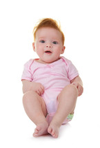 Smiling baby in pink jumpsuit sitting on the floor isolated on white background