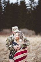 military couple wrapped in an American flag kissing 