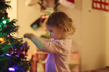 toddler girl decorating a Christmas tree 