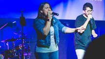 worship leaders singing into microphones 