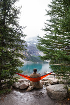 man in a hammock at a lake shore 