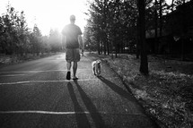 a man walking his dog on a leash at sunset 