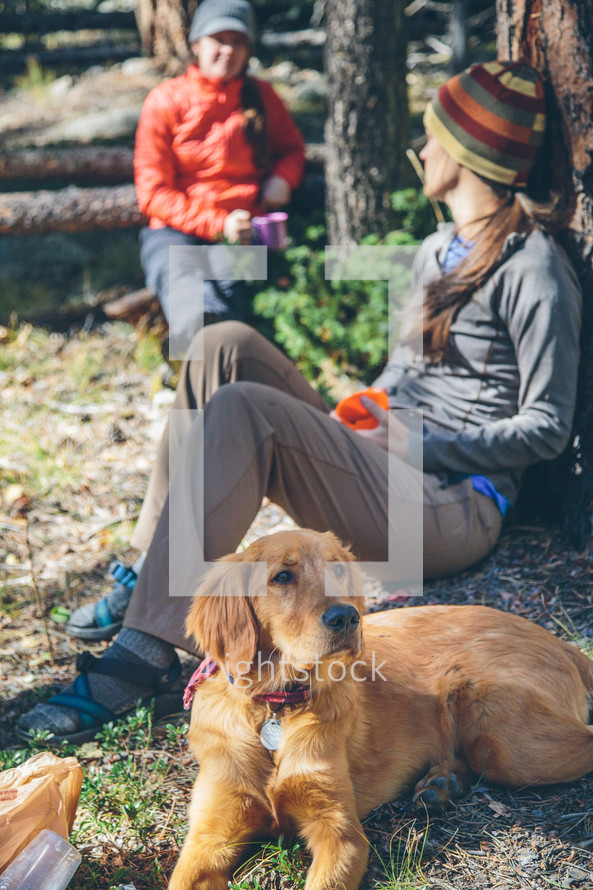 women campers sitting next to a dog 