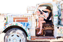 a woman sitting in an old truck painted with flowers 