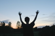 silhouette of a boy with his hands raised 