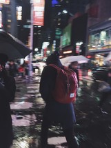 people on a crosswalk in NYC on a rainy night 