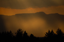 Eveningsun shining trough clouds on a mountain