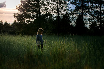 A young girl walking through a field of tall green grass 