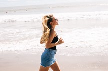 woman in a denim skirt running on beach 