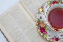 tea in a tea cup and an open book 