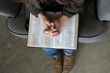a woman praying over and opened Bible in her lap 