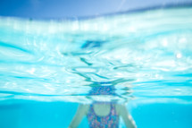 a girl child swimming under water in a pool 