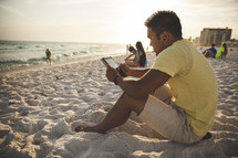man reading a tablet on a beach 