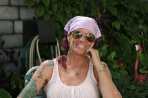 A tattooed woman in sunglasses and a bandana.