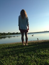 woman standing with her back to the camera in front of a lake 