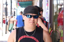 A young man in sunglasses and a backwards hat.