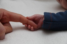 newborn holding a finger 