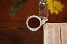 open Bible, flowers in a vase, and coffee mug on a table 