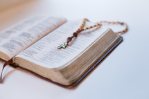 a wooden bead rosary on a Bible