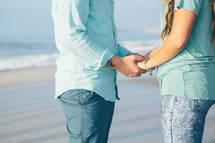 a couple holding hands on a beach 