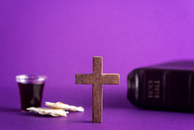communion elements, wood cross, and Bible on purple 