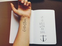 Arm tattoo and and journal -- "it is well with my soul."