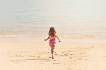 girl child running on a beach 