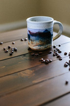 Coffee beans and a cup of coffee on a wooden table.