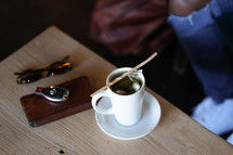 mug of tea on a table and car keys with wallet 