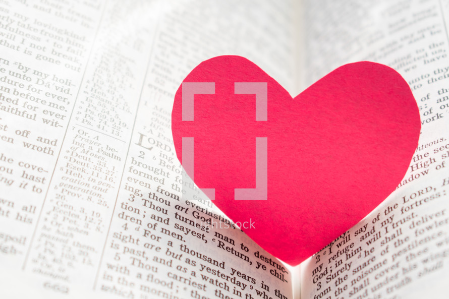 red paper heart between the pages of a Bible 