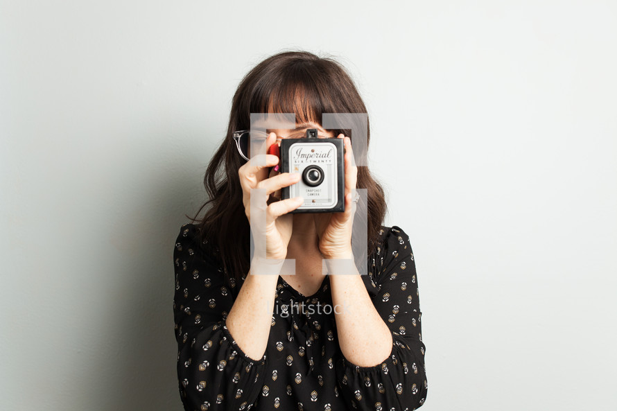 a woman taking a picture with an antique camera 