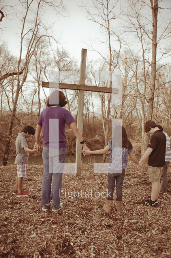 group holding hands in prayer around a cross