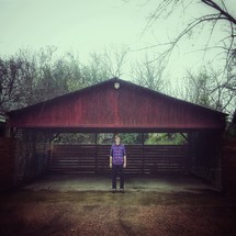 A man standing near a covered driveway. 
