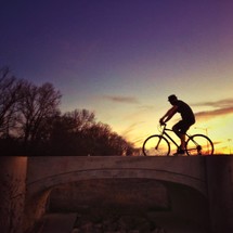 A man riding a bicycle at sunset