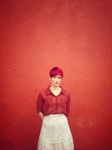 a woman standing in front of a red wall 