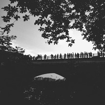 Silhouettes of people standing on a bridge. 