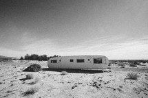 old, abandoned vacation trailer parked out in a desert