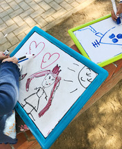 child coloring on a whiteboard outdoors 