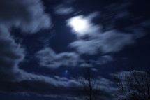 clouds in the night sky and the glow of a full moon