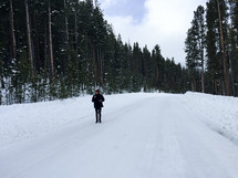 man standing in the middle of a snow covered road 