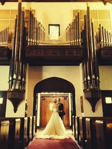 a bride and groom standing under organ pipes in a church 