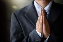 a man in a suit praying 